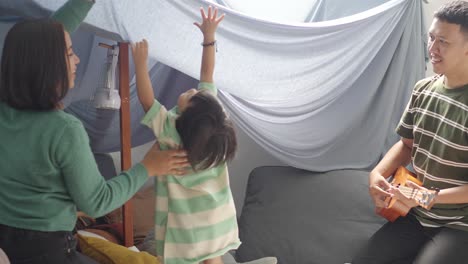 Young-Happy-Asian-Family-Having-Fun-In-A-Tent-That-They-Built-At-Home