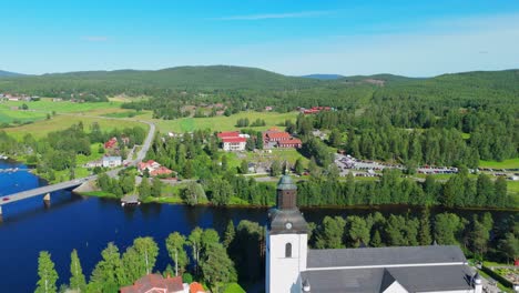 Aerial-view-of-church-in-the-tourist-resort-Järvsö,-Sweden-in-summer-sun---Establishing-shot