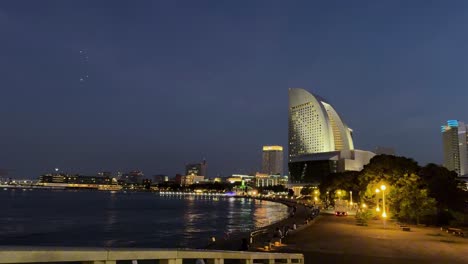 Vista-Panorámica-Del-Horizonte-De-La-Ciudad-Frente-Al-Mar-Por-La-Noche-Con-Edificios-Iluminados-Y-Aguas-Tranquilas