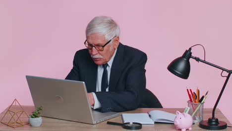 Senior-business-office-man-analyzes-financial-charts-celebrate-success-win-at-home-workplace-desk