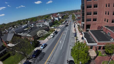 Aerial-descending-flight-along-church-tower-and-houses-on-main-street-in-summer