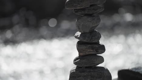 Close-up-of-balanced-stone-piles-by-a-tranquil-riverside,-emphasizing-natural-balance-and-serenity