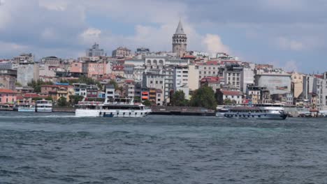 View-of-the-Galata-Tower-in-Istanbul,-Turkey,-with-a-water-bay-in-front-where-touristic-ships-are-docking