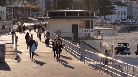 Medium-shot-of-people-walking-along-a-walking-path-at-sunrise,-Bondi-Beach