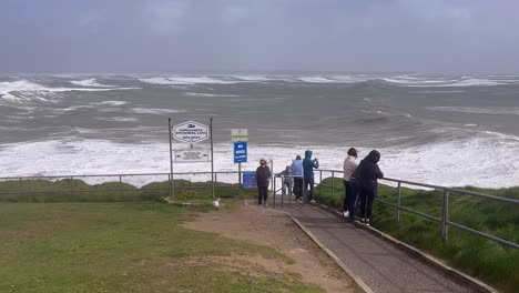 Angry-nature-ocean-storm-waves-roll-in-as-people-gather-above-to-watch