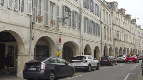 Profile-view-of-old-town-in-La-Rochelle,-France-with-cars-parked-beside-on-road-during-daytime