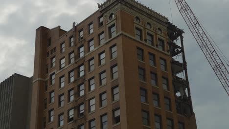 A-mid-demolition-view-of-a-high-rise-building-in-Youngstown,-Ohio,-showing-the-upper-floors-partially-dismantled-with-a-crane-on-site