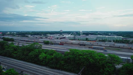 Aerial-view-of-a-railroad-terminal-with-multiple-tracks,-freight-trains,-and-industrial-buildings-in-the-background-on-a-cloudy-day