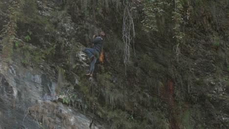 Drohnenaufnahme-Eines-Bauern,-Der-An-Einem-Seil-Hochklettert,-Um-Medizinischen-Honig-Von-Einer-Gefährlichen-Klippe-In-Nepal-Zu-Ernten