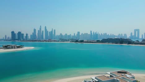 Aerial-footage-capturing-the-Dubai-skyline-from-the-fronds-of-Palm-Jumeirah,-showcasing-the-city's-architecture-and-serene-waters