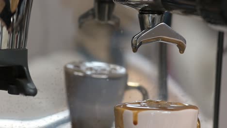 Сoffee-pouring-from-portafilter-of-coffee-machine-into-espresso-cup,-espresso-making-process