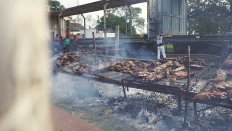 Outdoor-Argentine-grill-packed-with-large-beef-cuts,-billowing-smoke---slow-motion