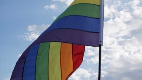 Bandera-Del-Movimiento-LGBT-Ondeando-Contra-Un-Cielo-Azul,-Simbolizando-Orgullo-Y-Libertad