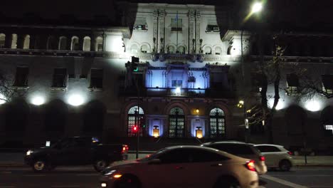 Panoramic-of-the-banking-polyclinic-hospital-on-Gaona-Avenue,-with-traffic-illuminated-with-neon-at-night-in-the-city-of-Buenos-Aires,-Argentina