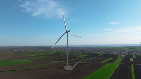 Wind-turbine-standing-tall-in-a-vast-green-and-brown-agricultural-landscape-under-a-clear-blue-sky