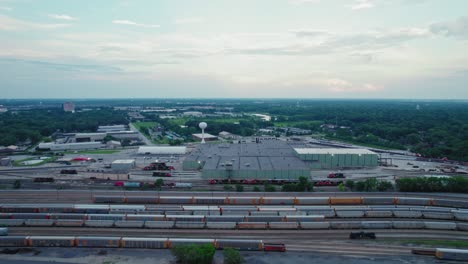 Aerial-shot-of-the-Homewood,-Illinois-railroad-terminal-with-multiple-freight-trains,-tracks,-and-industrial-buildings-under-a-cloudy-sky