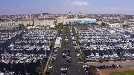 Aerial-reverse-pullback-descending-shot-of-the-long-parking-lot-dividing-King-Harbor-Marina-in-Redondo-Beach,-California