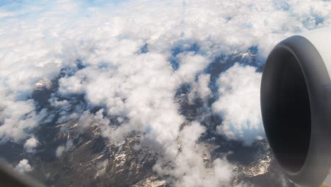 Flugzeug-Fliegt-über-Schneebedeckte-Berge-Mit-Weißen-Wolken