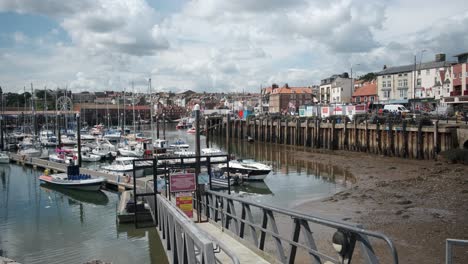 footage-of-Scarborough-Harbour,-North-Yorkshire-on-a-summer-day-the-harbor-has-boats-and-people-walking-around