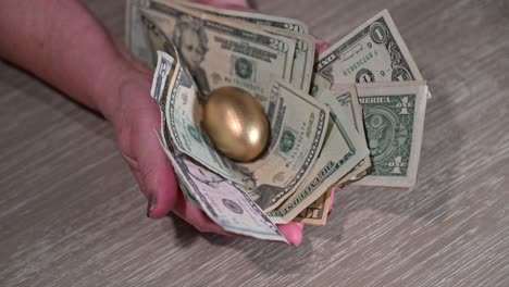 elderly-female-hands-show-a-retirement-nest-egg-of-cash-and-a-golden-egg-symbolizing-retiremnet