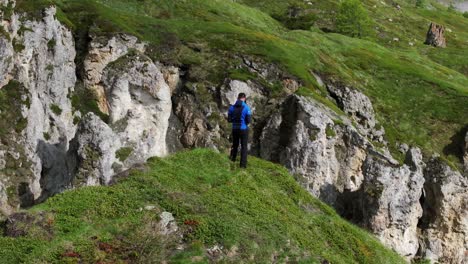 Man-hiker-standing-on-edge-of-cliff-contemplates-mountain-landscape-and-peaks-of-Mont-Cenis-in-France