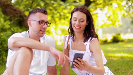 Pareja-Feliz-Con-Teléfono-Inteligente-En-Un-Picnic-En-El-Parque.-Concepto-De-Ocio-Y-Personas.-Pareja-Feliz-Con-Teléfono-Inteligente-Haciendo-Un-Picnic-En-El-Parque-De-Verano.