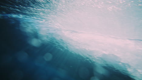 Underwater-pan-across-back-of-wave-crashing-as-vortex-forms-at-surface