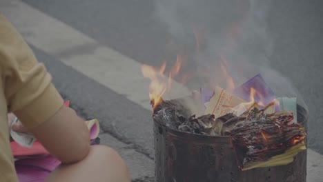 Vietnamese-ritual-of-burning-fake-money,-joss-paper-for-offering-on-sidewalk,-Hanoi