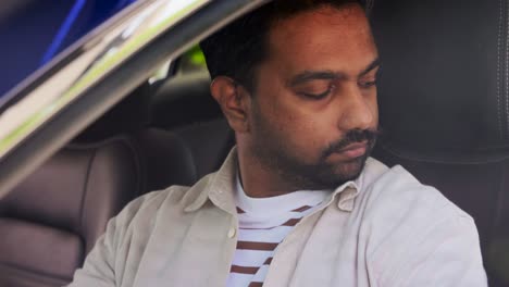 Smiling-Indian-Man-or-Driver-Driving-Car.transport,-safety-and-people-concept-happy-smiling-indian-man-or-driver-fastening-seat-belt-in-car