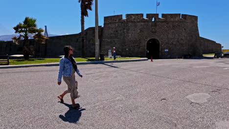 Mujer-Blanca-Caminando-Por-El-Muelle-Del-Puente-De-Río-En-Grecia-En-Un-Día-Caluroso,-Puente-Al-Fondo,-Cámara-Lenta-Y-Espacio-De-Copia