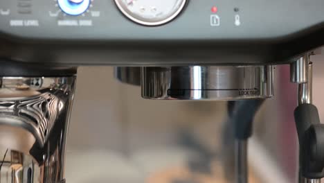 Barista-puts-holder-from-coffee-machine,-close-up