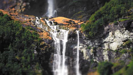 A-miniaturized-close-up-view-of-a-two-tier-waterfall-on-the-forest-covered-cliffs-above-the-Loenvatnet-lake