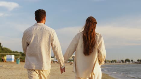 Happy-Couple-Walking-Along-Summer-Beach.summer-holidays-and-people-concept-happy-couple-walking-along-beach-in-tallinn,-estonia