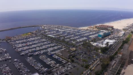 Wide-panning-aerial-shot-of-the-King-Harbor-Marina-towards-the-Pacific-Ocean-in-Redondo-Beach,-California