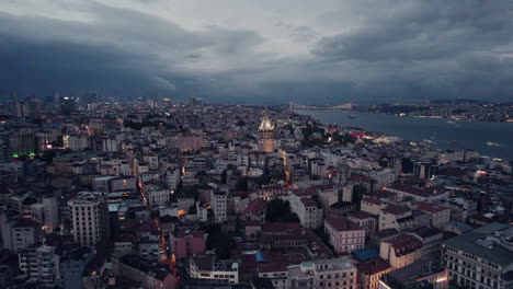 The-stunning-galata-tower-in-the-evening-with-lights,-surrounded-by-the-city-of-Istanbul,-copy-space-and-slow-motion