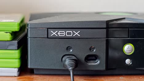 Encender-Y-Quitar-Un-Disco-De-Juego-De-Una-Consola-De-Juegos-Xbox-2001-Con-Luces-Verdes-Y-Naranjas