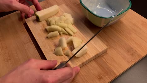 Male-hands-cutting-a-pear-and-put-it-into-a-bowl-with-a-knife