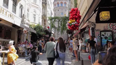 Una-Toma-En-Cámara-Lenta-De-Turistas-Comiendo-Y-Tomándose-Fotos-En-Un-Famoso-Callejón-Cerca-De-La-Torre-De-Gálata.