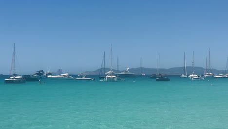 Veleros-Anclados-En-Las-Aguas-Turquesas-De-Mallorca,-España,-Bajo-Un-Cielo-Azul-Claro