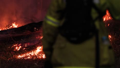 Firefighter-walks-past-a-hazard-reduction-burn,-Mount-Coot-tha