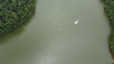 Two-boats-are-driving-into-a-cove-with-a-wake-and-come-to-a-stop-as-they-are-getting-ready-to-anchor