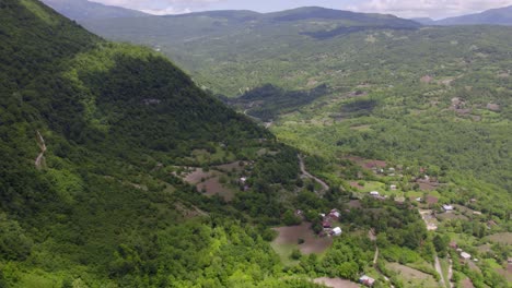 Vista-Aérea-De-Un-Remoto-Pueblo-Georgiano-En-Las-Montañas-Boscosas-Con-Sombras-Proyectadas-Por-Las-Nubes-Arriba