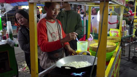 Vendedor-Ambulante-Cocinando-Telur-Gulung,-Un-Rollo-De-Huevo-Frito-Indonesio,-En-Un-Mercado-Concurrido