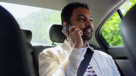 Male-Passenger-Calling-on-Smartphone-in-Taxi-Car.transport,-business-and-technology-concept-happy-smiling-indian-male-passenger-or-businessman-using-voice-command-recorder-on-smartphone-on-back-seat-of-taxi-car