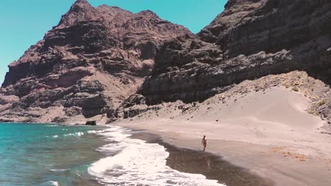 Idyllic-scene-of-a-woman-relaxing-unwinding-at-unspoiled-virgin-beach-in-Gran-Canaria,-Spain-during-summer-time-on-vacations