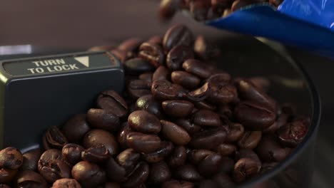 Macro-view-of-coffee-beans-spill-out-of-the-bag-to-the-grinder