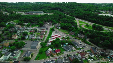 Aerial-view-of-Pittsburgh-suburbs-with-houses,-winding-roads,-trees,-and-nearby-industrial-area