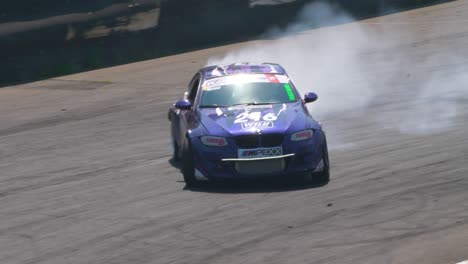 Dos-Autos-De-Carrera-Derrapando-En-Una-Curva-Muy-Cerrada-Con-Mucho-Humo,-Seguidos-De-Cerca-Por-Un-Dron.