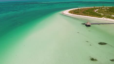 Vista-Aérea-De-La-Isla-Holbox-Que-Muestra-Agua-Clara,-Playa-De-Arena-Blanca-Y-Cabaña-De-Madera.