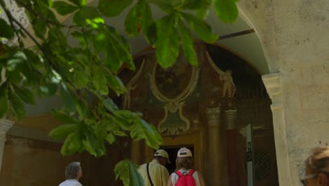 Tourists-walk-through-entrance-door-of-historic-church-building-in-Turin,-Italy